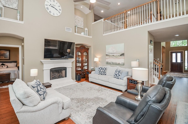 24511 Pelican Hill Dr, Katy, TX 77494 - living area with a high ceiling, wood finished floors, a ceiling fan, a fireplace with raised hearth, and stairs