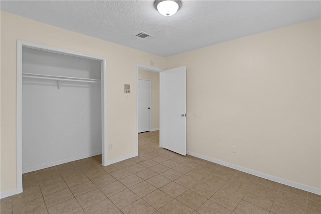 10211 Golden Meadow Dr, Houston, TX 77064 - unfurnished bedroom featuring a textured ceiling, a closet, light tile patterned floors, and baseboards