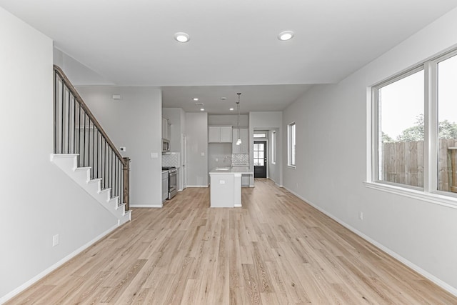 19253 Hazel Firs Ct, Magnolia, TX 77355 - unfurnished living room with light wood-style flooring, a sink, baseboards, recessed lighting, and stairway