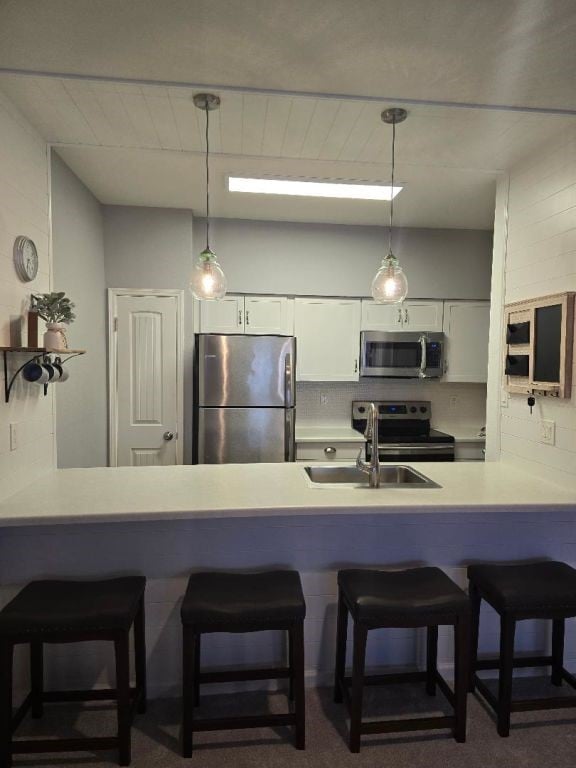 334 Wilcrest Dr Unit 334, Houston, TX 77042 - kitchen featuring stainless steel appliances, a peninsula, a sink, white cabinets, and hanging light fixtures
