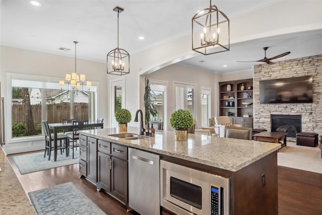 1746 Du Barry Ln, Houston, TX 77018 - kitchen featuring stainless steel appliances, a sink, a stone fireplace, light stone countertops, and crown molding