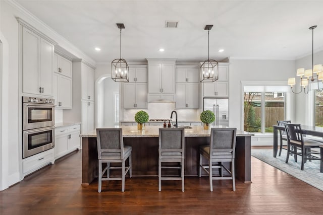 1746 Du Barry Ln, Houston, TX 77018 - kitchen featuring stainless steel appliances, a chandelier, arched walkways, a large island with sink, and ornamental molding