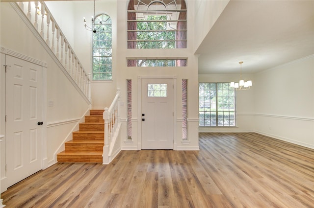 16727 Camber Ct, Crosby, TX 77532 - foyer entrance featuring a chandelier, stairs, light wood-style flooring, a high ceiling, and baseboards