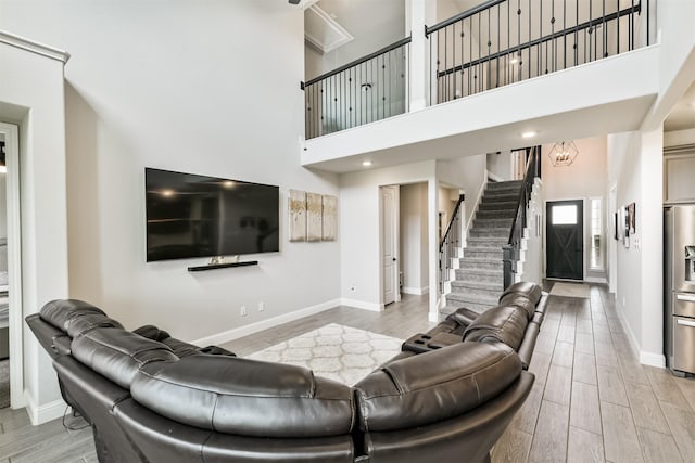 19303 Belmont Stakes Way, Tomball, TX 77377 - living room featuring light wood-type flooring, a towering ceiling, baseboards, and stairway