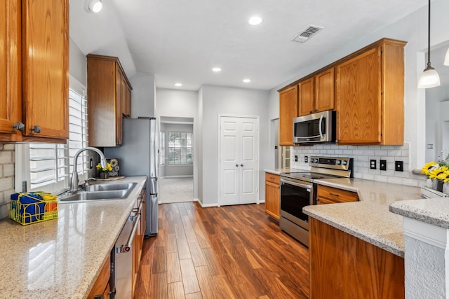 9515 Willow Crossing Dr, Houston, TX 77064 - kitchen with appliances with stainless steel finishes, dark wood-type flooring, brown cabinets, a sink, and recessed lighting