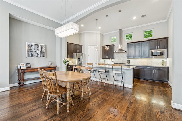 6123 Stillman St, Houston, TX 77007 - dining room featuring ornamental molding, dark wood-style floors, arched walkways, recessed lighting, and baseboards
