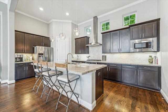 6123 Stillman St, Houston, TX 77007 - kitchen featuring wall chimney range hood, stainless steel appliances, dark brown cabinets, a kitchen bar, and crown molding