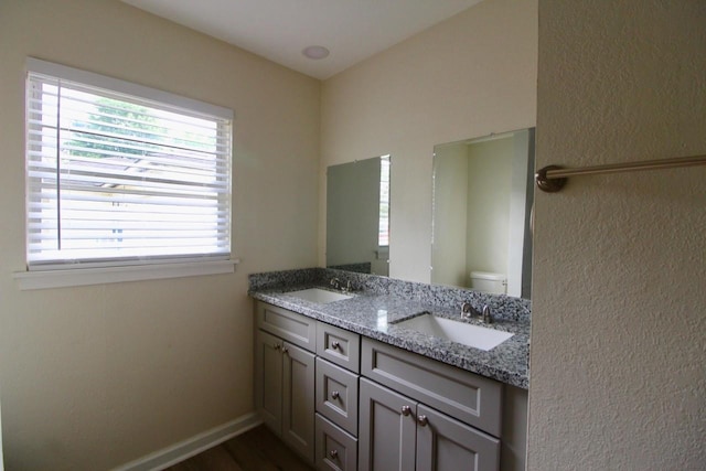 1215 Maplewood Ln, Pasadena, TX 77502 - full bath featuring double vanity, toilet, wood finished floors, baseboards, and a textured wall