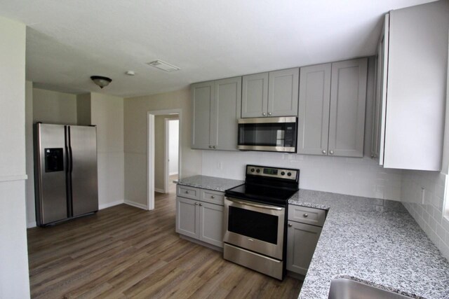 1215 Maplewood Ln, Pasadena, TX 77502 - kitchen with stainless steel appliances, gray cabinets, backsplash, wood finished floors, and light stone counters