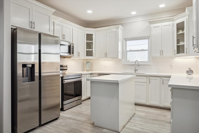22409 Vista Del Mar, Galveston, TX 77554 - kitchen with stainless steel appliances, a sink, white cabinetry, light countertops, and light wood-style flooring