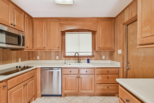 2920 Heron Dr, Galveston, TX 77551 - kitchen featuring stainless steel appliances, a sink, light tile patterned flooring, light countertops, and wood walls