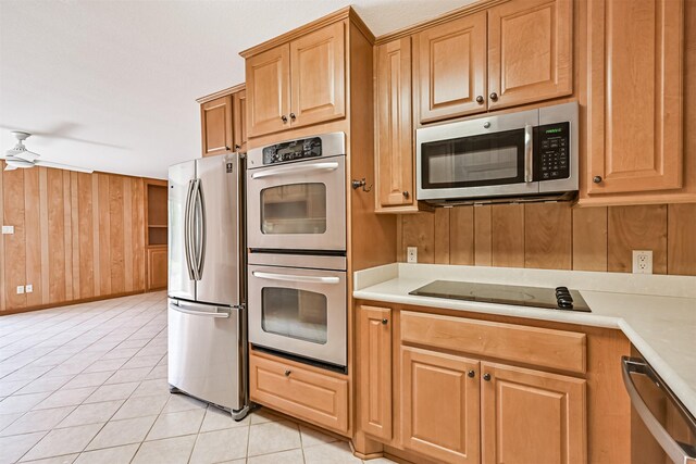 2920 Heron Dr, Galveston, TX 77551 - kitchen featuring stainless steel appliances, light countertops, wood walls, light tile patterned floors, and a ceiling fan