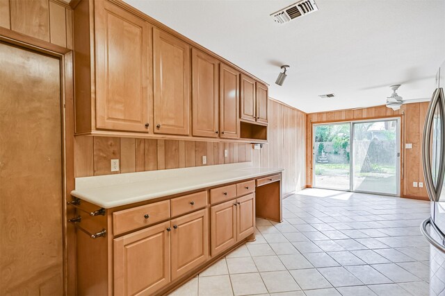 2920 Heron Dr, Galveston, TX 77551 - kitchen with light countertops, freestanding refrigerator, light tile patterned flooring, wooden walls, and ceiling fan