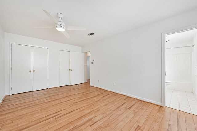 2920 Heron Dr, Galveston, TX 77551 - unfurnished bedroom with two closets, light wood-type flooring, ensuite bath, and baseboards