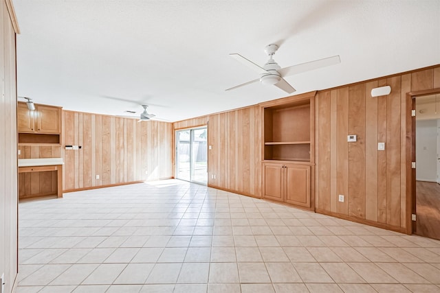 2920 Heron Dr, Galveston, TX 77551 - unfurnished living room with ceiling fan, wooden walls, built in shelves, baseboards, and light tile patterned flooring