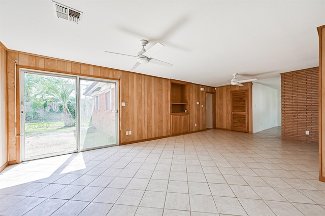 2920 Heron Dr, Galveston, TX 77551 - unfurnished living room with a ceiling fan, wood walls, built in features, baseboards, and light tile patterned floors