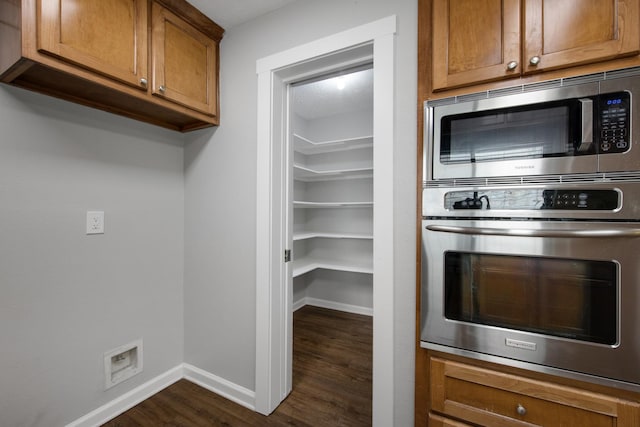 15735 Mesa Gardens Dr, Houston, TX 77095 - kitchen with stainless steel appliances, dark wood-style flooring, brown cabinetry, and baseboards