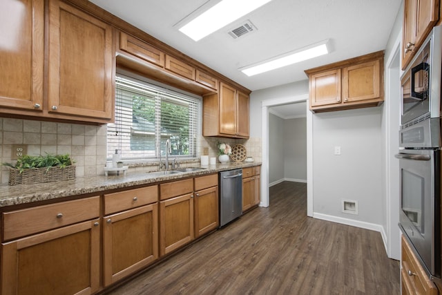 15735 Mesa Gardens Dr, Houston, TX 77095 - kitchen with appliances with stainless steel finishes, a sink, brown cabinets, and baseboards