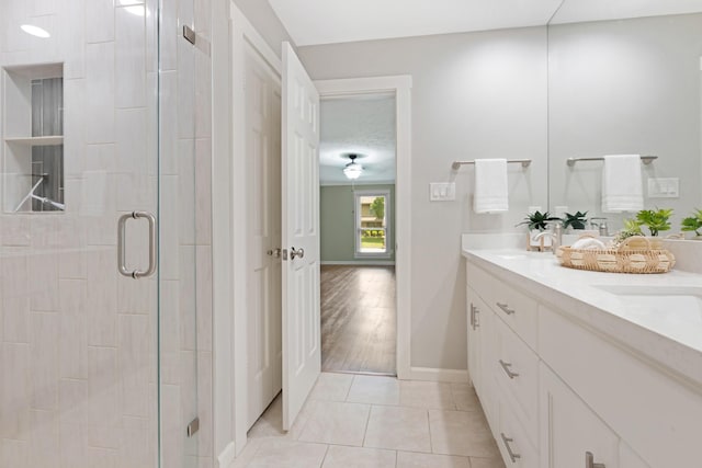 15735 Mesa Gardens Dr, Houston, TX 77095 - bathroom featuring a stall shower, double vanity, tile patterned flooring, and baseboards
