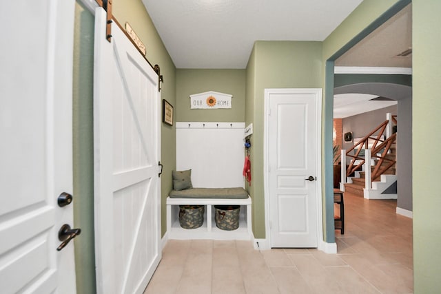 5131 Kingship Ct, Katy, TX 77493 - mudroom featuring a barn door, arched walkways, light tile patterned floors, and baseboards