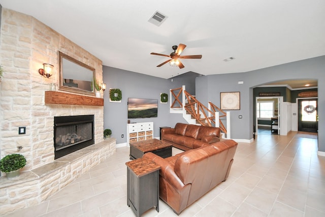 5131 Kingship Ct, Katy, TX 77493 - living area with arched walkways, light tile patterned flooring, a stone fireplace, stairs, and a ceiling fan