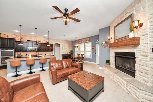 5131 Kingship Ct, Katy, TX 77493 - living area with light tile patterned flooring, ceiling fan, arched walkways, a stone fireplace, and recessed lighting