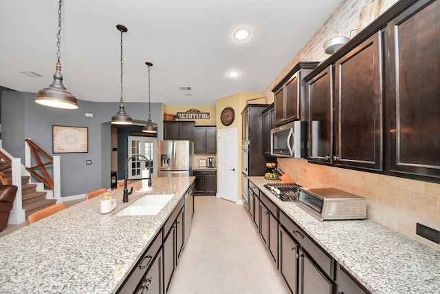 5131 Kingship Ct, Katy, TX 77493 - kitchen with appliances with stainless steel finishes, a sink, backsplash, light stone counters, and pendant lighting