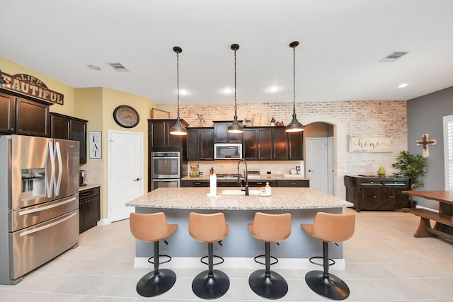 5131 Kingship Ct, Katy, TX 77493 - kitchen with appliances with stainless steel finishes, arched walkways, a sink, a breakfast bar area, and recessed lighting