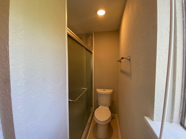 14311 Waterloo Dr, Houston, TX 77045 - bathroom featuring toilet, a stall shower, a textured wall, and baseboards
