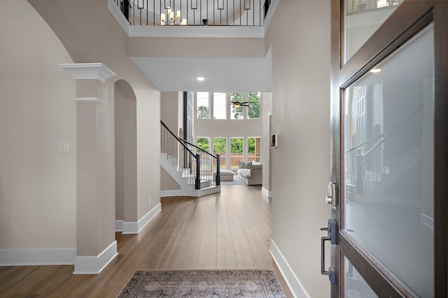8211 Barristan Bluffs Ct, Magnolia, TX 77354 - foyer featuring a towering ceiling, stairs, baseboards, arched walkways, and wood finished floors