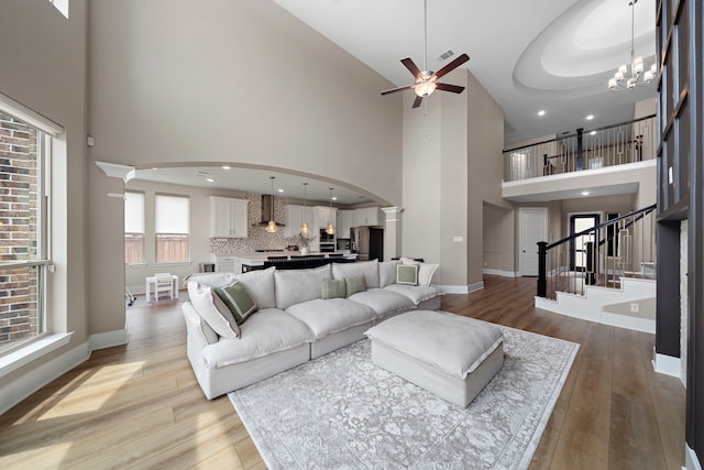 8211 Barristan Bluffs Ct, Magnolia, TX 77354 - living area with arched walkways, a towering ceiling, decorative columns, light wood-style flooring, and ceiling fan