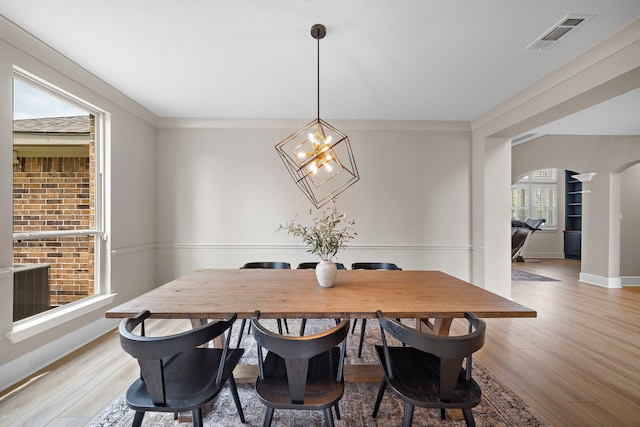 8211 Barristan Bluffs Ct, Magnolia, TX 77354 - dining area with arched walkways, light wood-style flooring, a chandelier, and baseboards