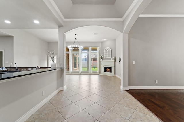 19403 Shady Edge Dr, Cypress, TX 77433 - kitchen with a sink, light tile patterned floors, baseboards, crown molding, and a lit fireplace