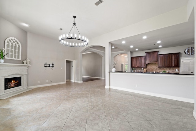 19403 Shady Edge Dr, Cypress, TX 77433 - unfurnished living room with arched walkways, recessed lighting, light tile patterned floors, a chandelier, and a high end fireplace