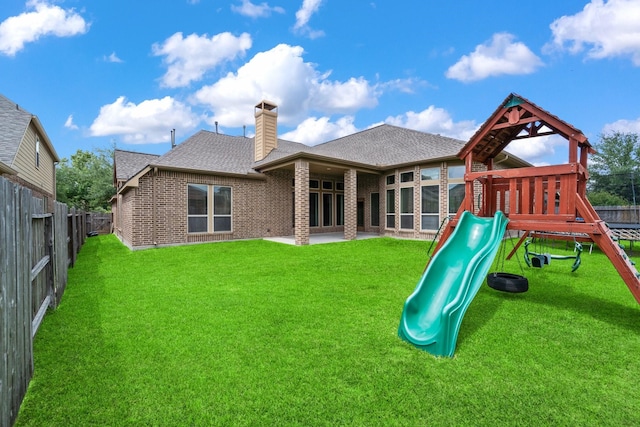 19403 Shady Edge Dr, Cypress, TX 77433 - rear view of house with a playground, a shingled roof, brick siding, and a chimney