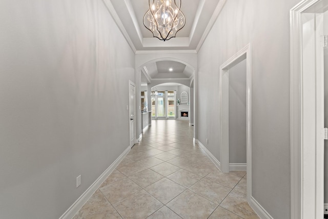 19403 Shady Edge Dr, Cypress, TX 77433 - corridor with arched walkways, a chandelier, baseboards, light tile patterned floors, and a tray ceiling