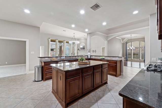 19403 Shady Edge Dr, Cypress, TX 77433 - kitchen featuring a chandelier, arched walkways, a kitchen island, light tile patterned floors, and recessed lighting
