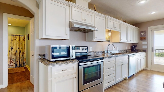 1508 Galveston Ave, Port Bolivar, TX 77650 - kitchen with under cabinet range hood, appliances with stainless steel finishes, a sink, light wood finished floors, and stone counters