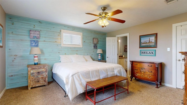 1508 Galveston Ave, Port Bolivar, TX 77650 - bedroom featuring light carpet, baseboards, wood walls, ensuite bathroom, and a ceiling fan