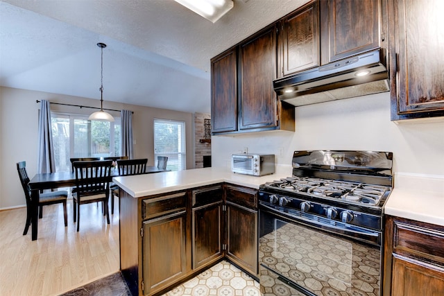 8123 Sweetgum Trace Dr, Houston, TX 77040 - kitchen with black gas range oven, under cabinet range hood, light countertops, vaulted ceiling, and a peninsula