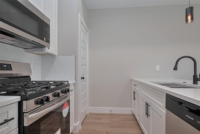 7911 Carver Rd, Houston, TX 77088 - kitchen with stainless steel appliances, a sink, tasteful backsplash, white cabinets, and light wood-style flooring