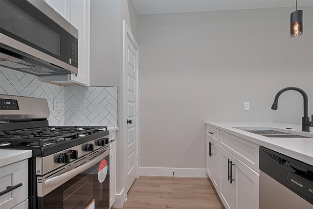 7911 Carver Rd, Houston, TX 77088 - kitchen featuring stainless steel appliances, backsplash, light wood-style floors, white cabinetry, and light countertops
