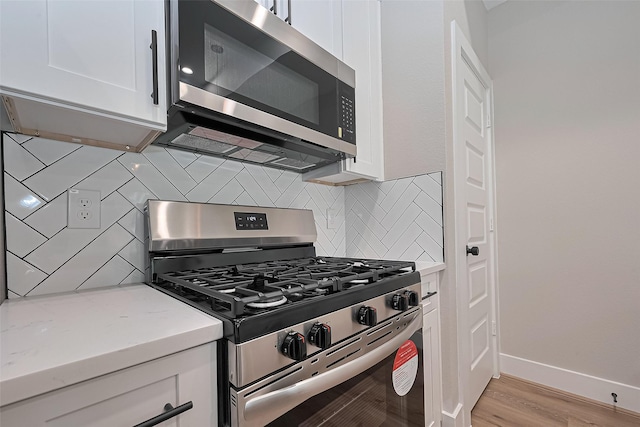 7911 Carver Rd, Houston, TX 77088 - kitchen with appliances with stainless steel finishes, white cabinets, decorative backsplash, and light stone countertops