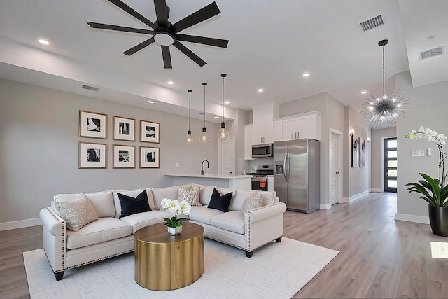 7911 Carver Rd, Houston, TX 77088 - living area with baseboards, light wood-type flooring, ceiling fan, recessed lighting, and a chandelier