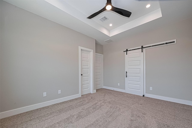 7911 Carver Rd, Houston, TX 77088 - unfurnished bedroom featuring a barn door, carpet floors, recessed lighting, a tray ceiling, and baseboards
