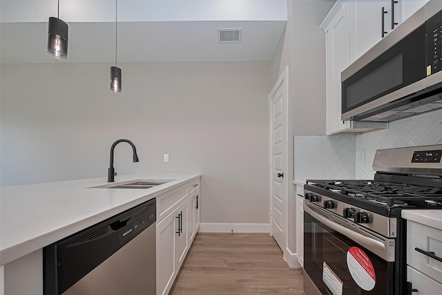 7911 Carver Rd, Houston, TX 77088 - kitchen featuring appliances with stainless steel finishes, a sink, backsplash, light wood finished floors, and light countertops