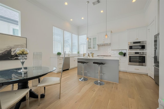 1205 Timbergrove Acres St, Houston, TX 77008 - kitchen featuring appliances with stainless steel finishes, ornamental molding, a breakfast bar, white cabinets, and backsplash