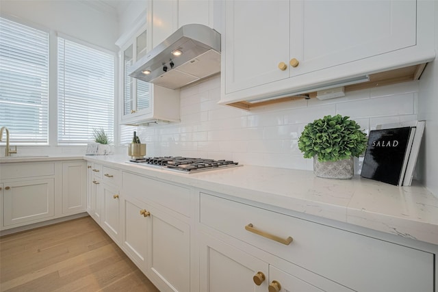 1205 Timbergrove Acres St, Houston, TX 77008 - kitchen with wall chimney range hood, stainless steel gas cooktop, decorative backsplash, white cabinetry, and light wood finished floors