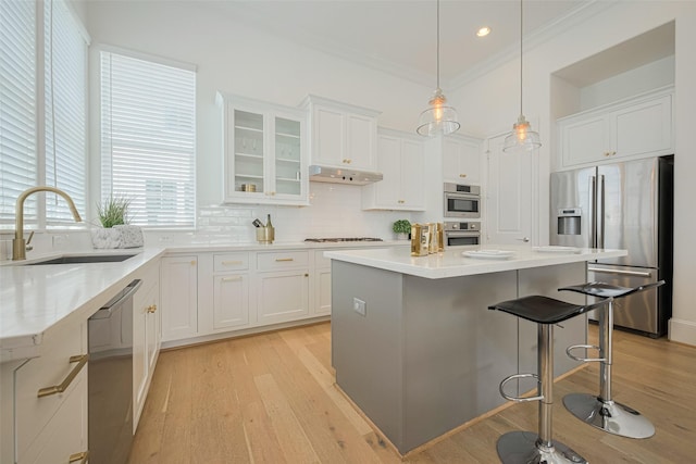 1205 Timbergrove Acres St, Houston, TX 77008 - kitchen featuring appliances with stainless steel finishes, light wood-style flooring, a breakfast bar area, ornamental molding, and white cabinets