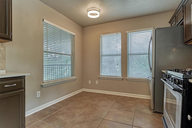 94 S Magnolia Pond Pl, The Woodlands, TX 77381 - kitchen featuring stainless steel range with gas cooktop, dark brown cabinetry, plenty of natural light, tile patterned floors, and a textured ceiling